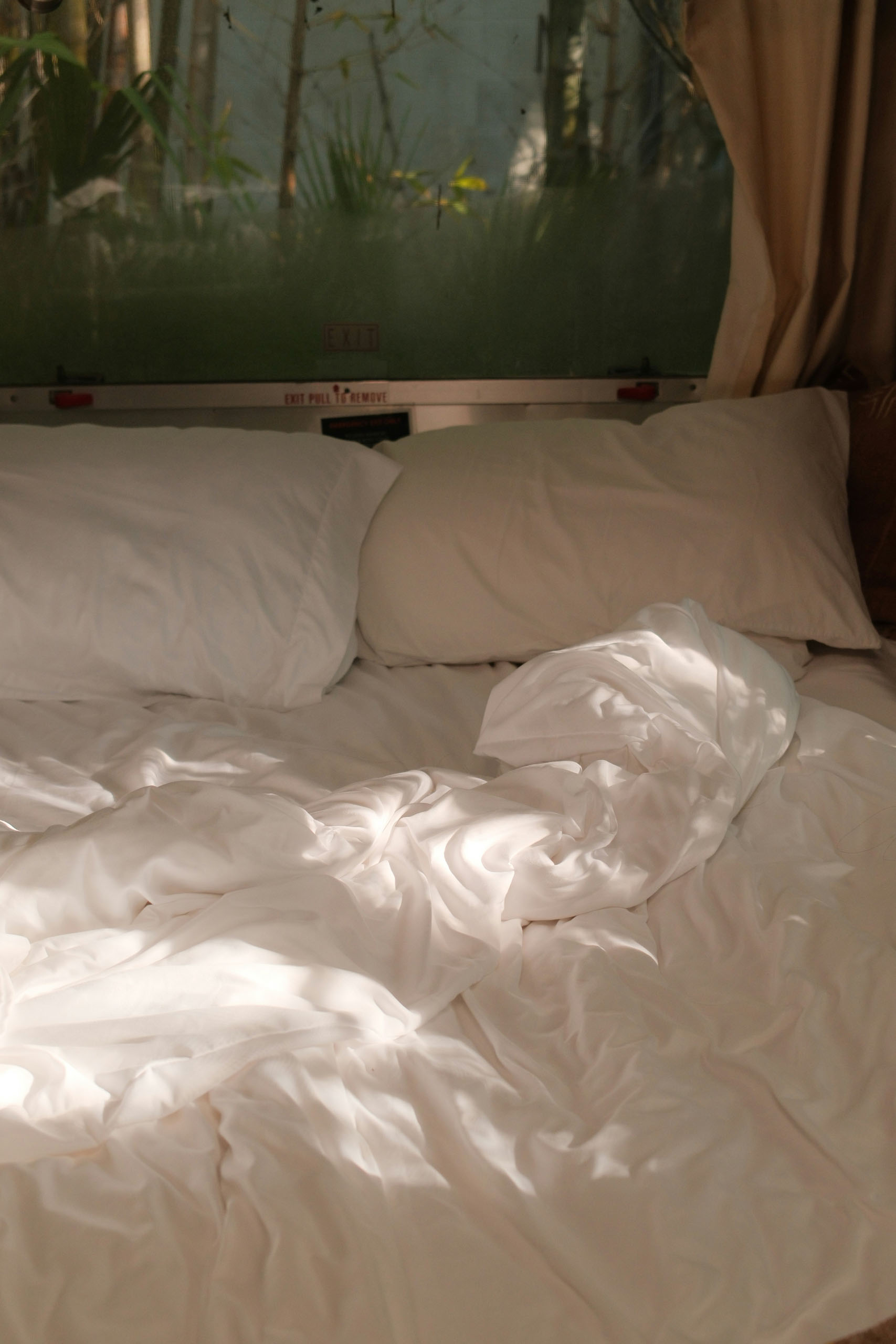 Bright white bedding with soft light through curtains